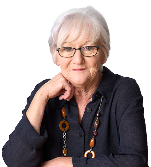 Professional headshot of Veronica Culleton, she has short white hair, and is wearing glasses and a dark shirt with a chunky brown and orange beaded necklace. She is resting her chin thoughtfully on her hand and smiling gently.