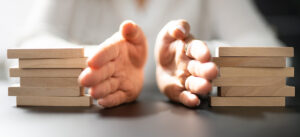 Close-up of two hands separating two equal stacks of wooden blocks on a table, symbolising division or distribution, possibly in a legal or financial context.