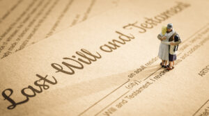 Close-up of a document titled 'Last Will and Testament' with miniature figurines of a family embracing, symbolising inheritance, legacy or end-of-life planning.